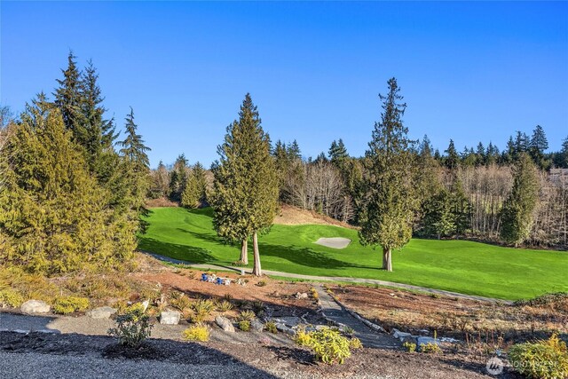 view of property's community featuring view of golf course and a lawn