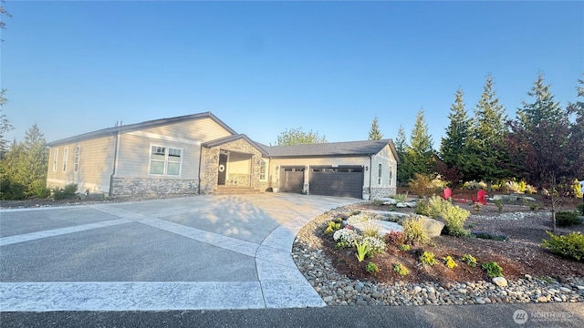 single story home with a garage, driveway, and stone siding