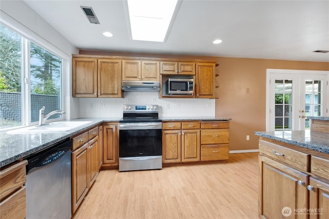 kitchen with stainless steel appliances, visible vents, a sink, light stone countertops, and under cabinet range hood