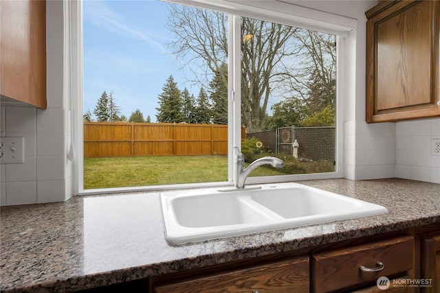 kitchen featuring brown cabinets, a sink, and backsplash