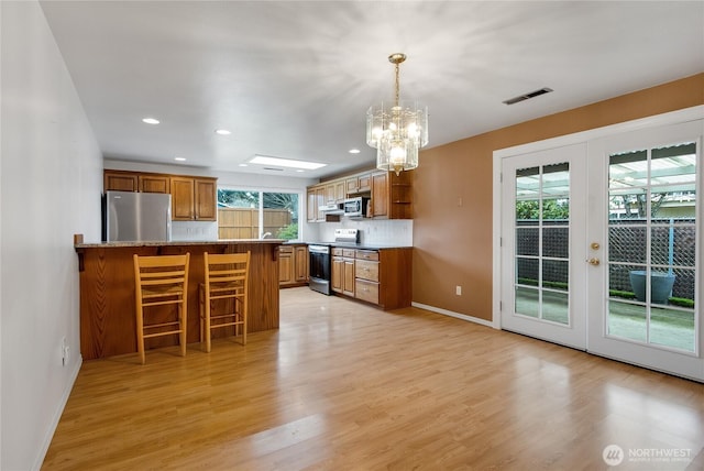 kitchen with stainless steel appliances, visible vents, light countertops, open shelves, and decorative light fixtures