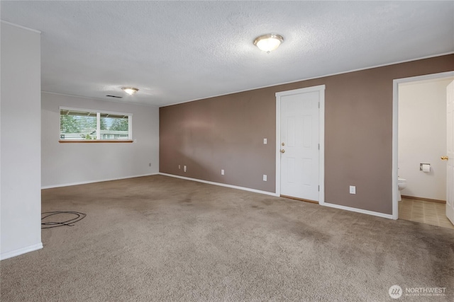 empty room featuring a textured ceiling, carpet flooring, and baseboards