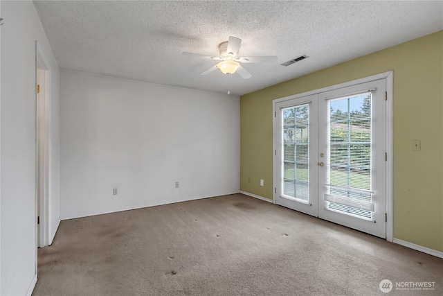 unfurnished room featuring ceiling fan, a textured ceiling, light carpet, visible vents, and french doors