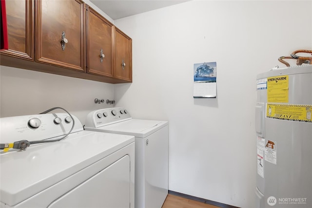 laundry room featuring washer and dryer, electric water heater, and cabinet space