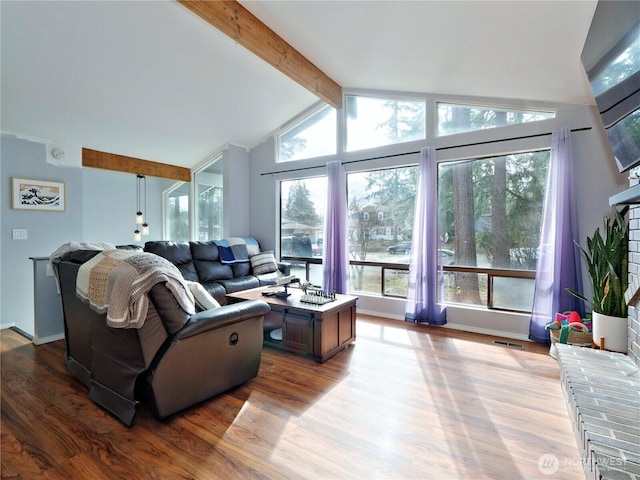 living room featuring lofted ceiling with beams, wood finished floors, visible vents, and baseboards