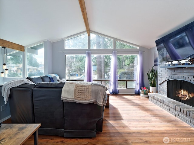 living room featuring a wealth of natural light, a fireplace, lofted ceiling with beams, and wood finished floors