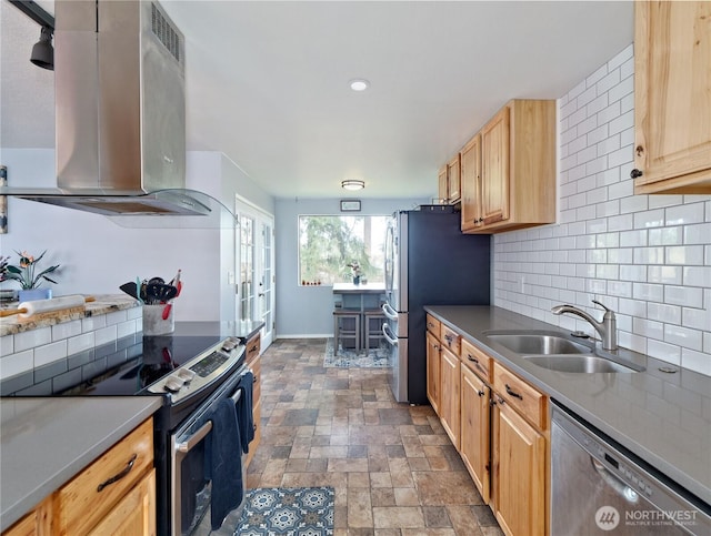 kitchen featuring decorative backsplash, appliances with stainless steel finishes, stone finish flooring, a sink, and ventilation hood