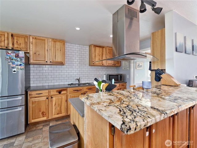 kitchen with tasteful backsplash, island range hood, stone finish floor, appliances with stainless steel finishes, and a sink