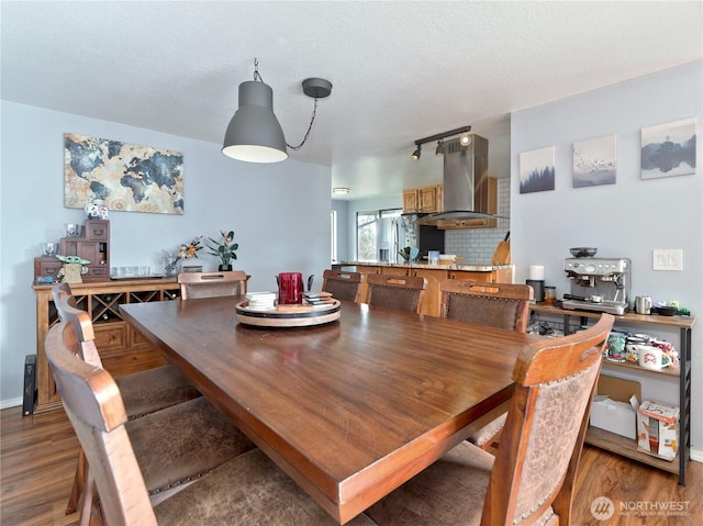 dining space with rail lighting, a textured ceiling, and wood finished floors