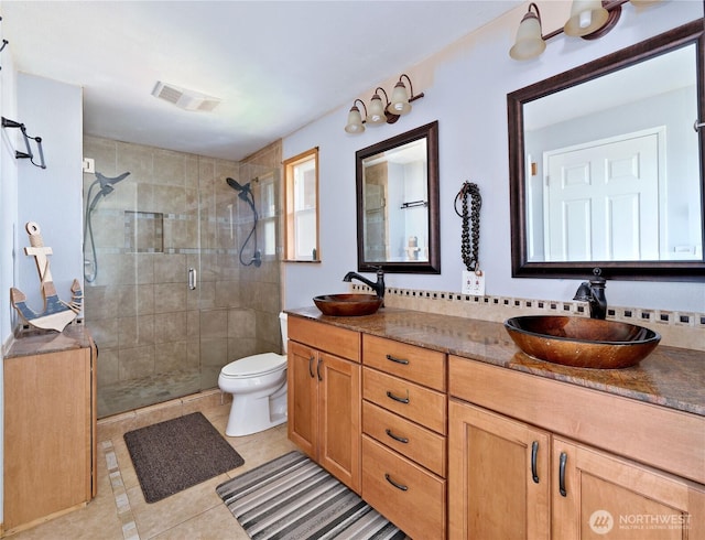 bathroom with toilet, a sink, visible vents, and a shower stall