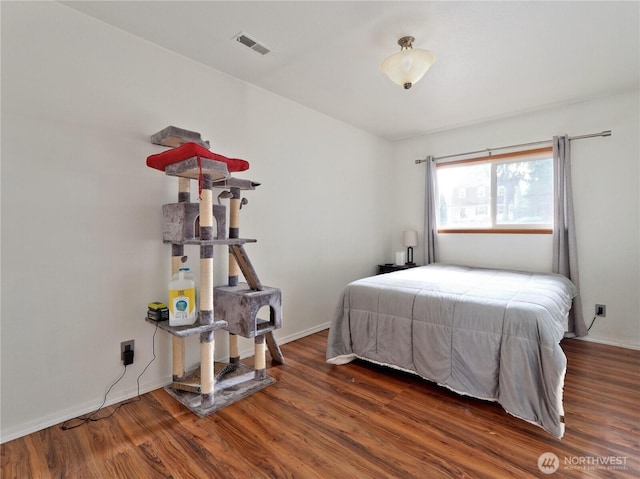 bedroom featuring wood finished floors, visible vents, and baseboards