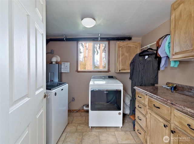 laundry area featuring stone finish floor, washer and clothes dryer, and cabinet space