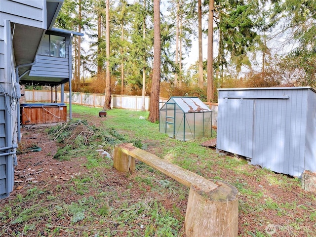 view of yard featuring an outbuilding, a fenced backyard, and a greenhouse