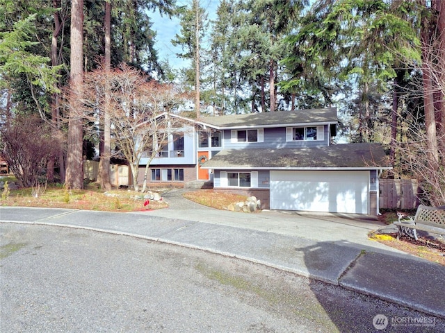 view of front facade featuring a garage, driveway, fence, and brick siding