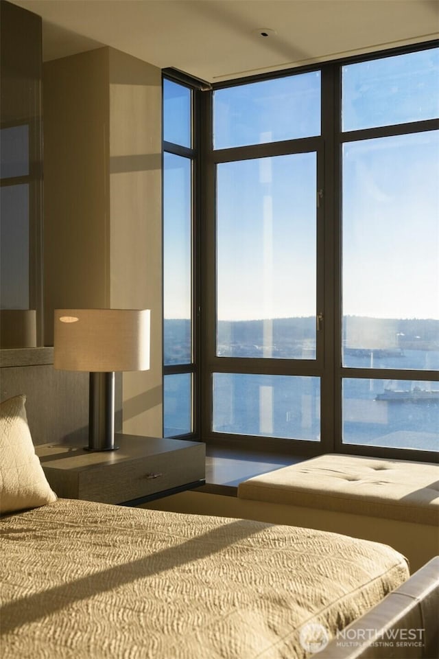 unfurnished bedroom with expansive windows, a water view, and multiple windows