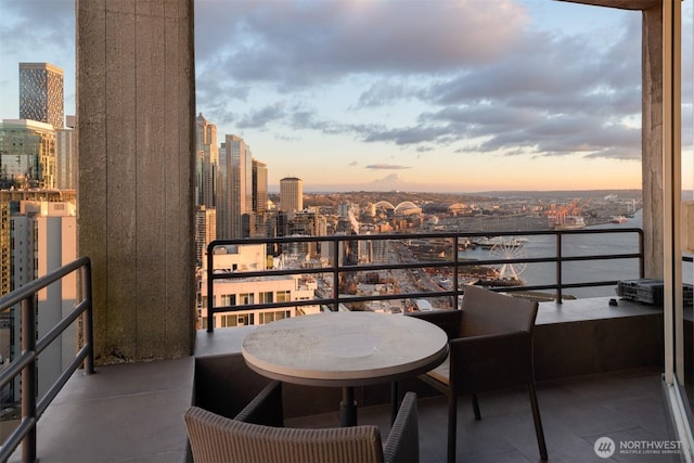 balcony at dusk with a view of city and a water view