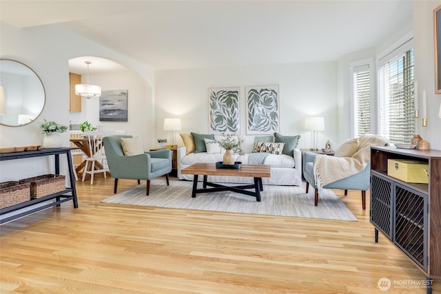 living area with light wood finished floors and arched walkways