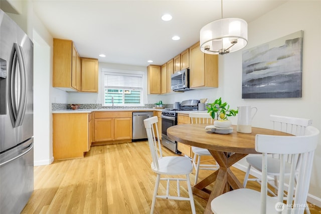 kitchen featuring light wood finished floors, hanging light fixtures, stainless steel appliances, light countertops, and light brown cabinetry