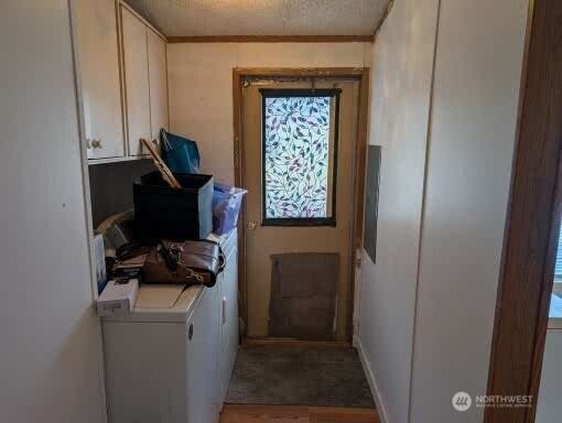 clothes washing area with cabinet space, a textured ceiling, and washer and dryer