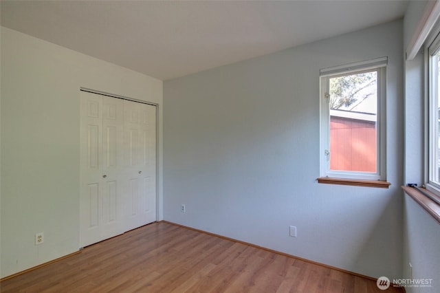 unfurnished bedroom featuring light wood-style floors and a closet