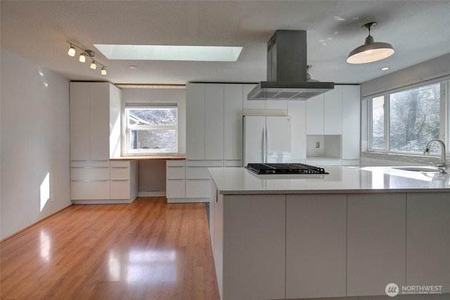 kitchen featuring island range hood, a sink, freestanding refrigerator, black stovetop, and modern cabinets