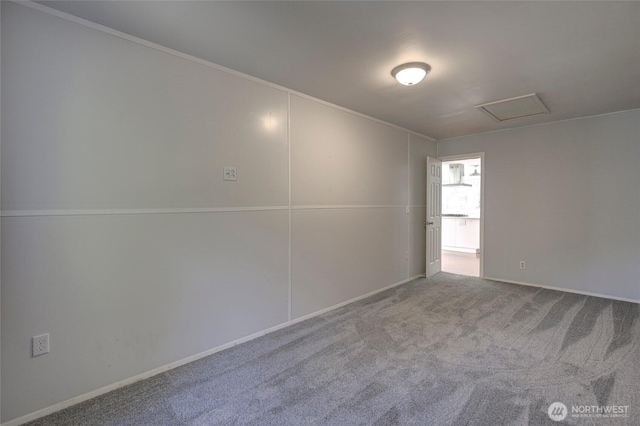 carpeted spare room featuring attic access