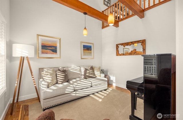 living room with beam ceiling, baseboards, and wood finished floors