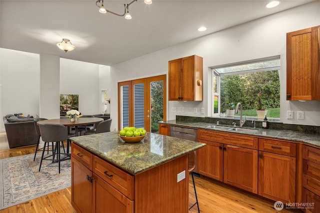 kitchen featuring light wood-type flooring, a breakfast bar, a sink, open floor plan, and a center island