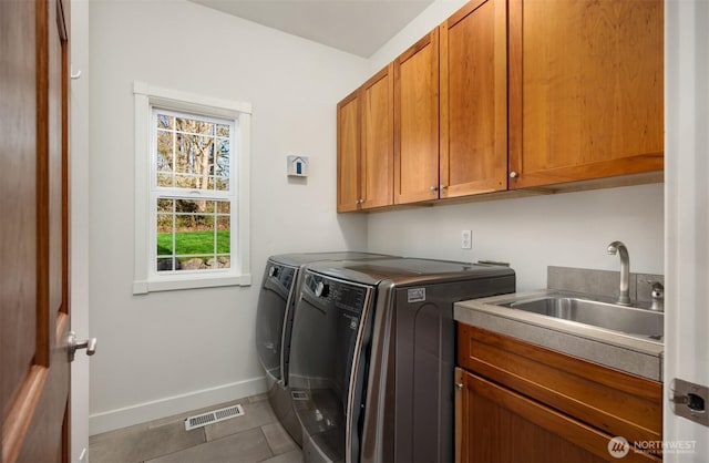 washroom featuring baseboards, visible vents, washing machine and clothes dryer, cabinet space, and a sink