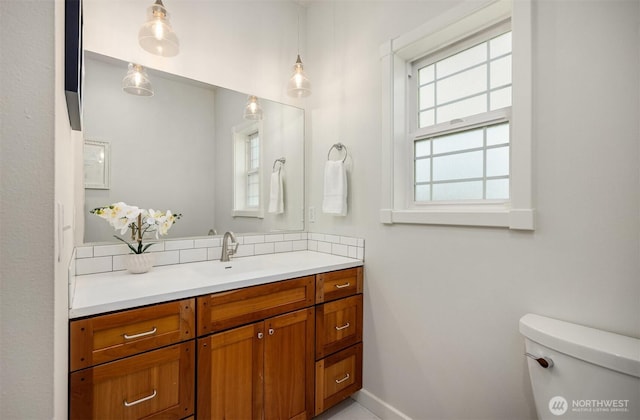 half bathroom with baseboards, toilet, and vanity