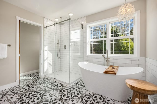 bathroom with a freestanding tub, tile patterned flooring, a shower stall, tile walls, and a notable chandelier