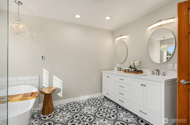 full bathroom featuring baseboards, double vanity, a freestanding tub, a sink, and tile patterned flooring