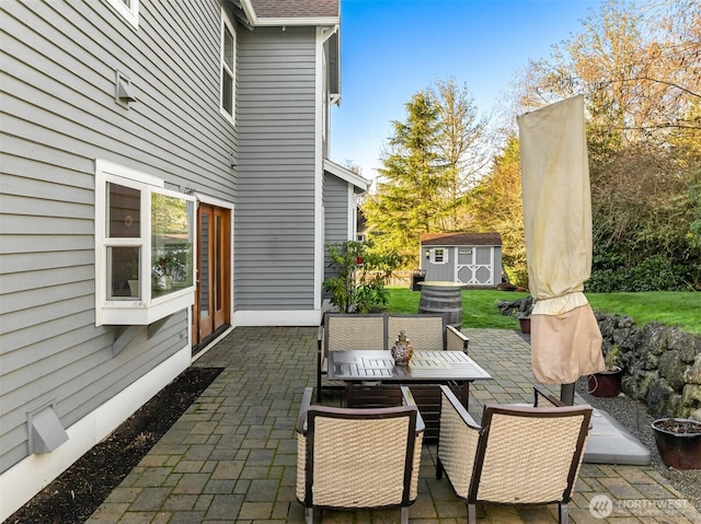 view of patio / terrace featuring an outbuilding, outdoor dining space, and a storage shed