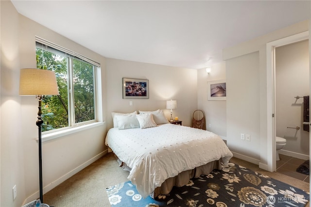 bedroom with carpet flooring, ensuite bath, and baseboards