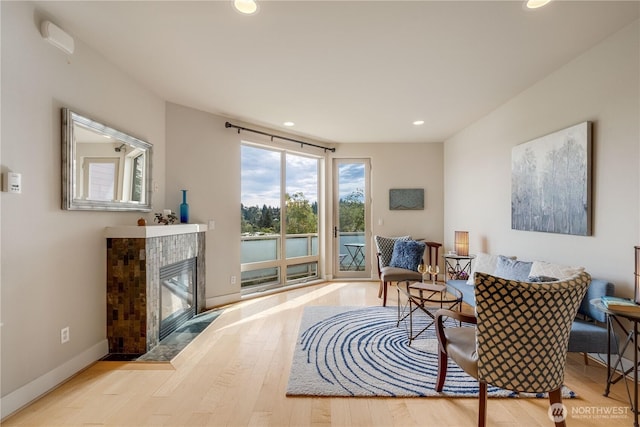 living area featuring light wood-type flooring, a fireplace, baseboards, and recessed lighting