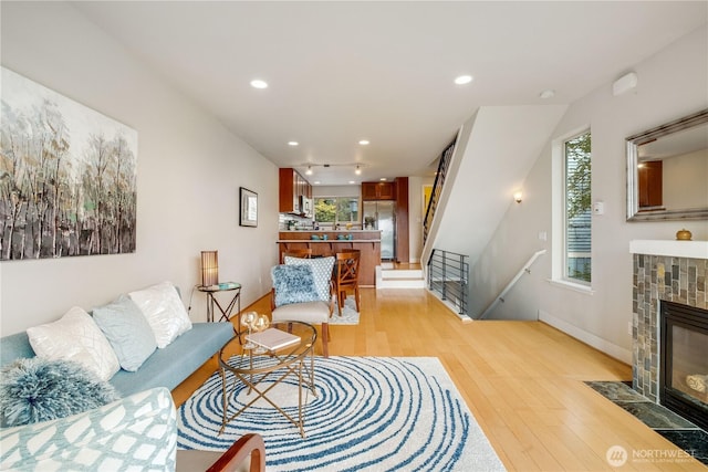 living room featuring recessed lighting, a fireplace, light wood-style flooring, and baseboards