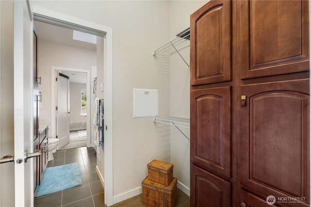 walk in closet with dark tile patterned flooring