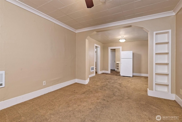 carpeted empty room featuring arched walkways, ornamental molding, and visible vents