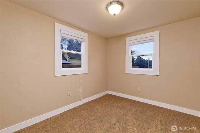 carpeted spare room featuring baseboards