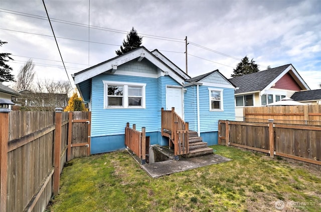 back of property featuring a fenced backyard and a lawn