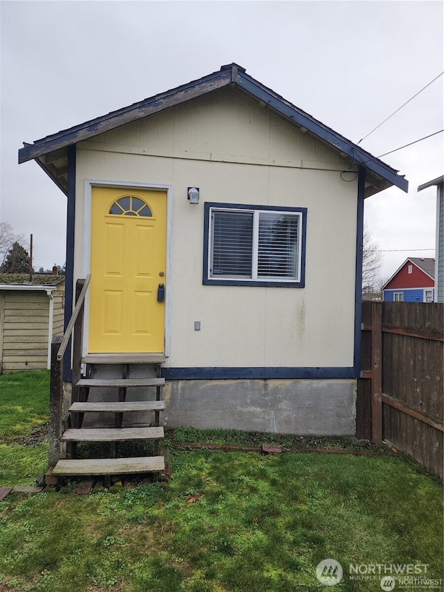 view of front of property with entry steps, fence, and a front yard