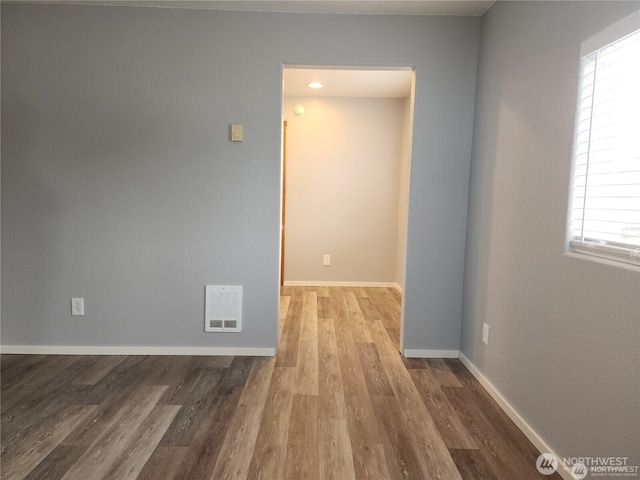 spare room featuring wood finished floors, visible vents, and baseboards