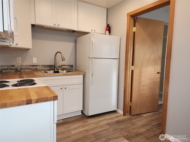 kitchen featuring white appliances, a sink, butcher block counters, and white cabinets