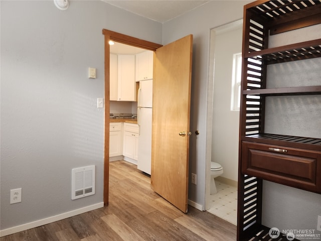 interior space featuring toilet, baseboards, visible vents, and wood finished floors