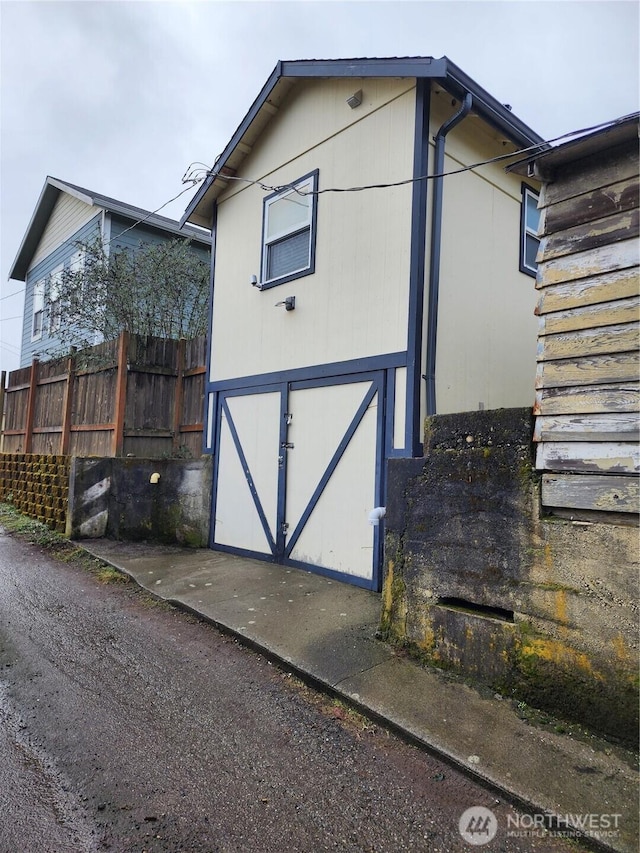 view of outdoor structure featuring fence and an attached garage