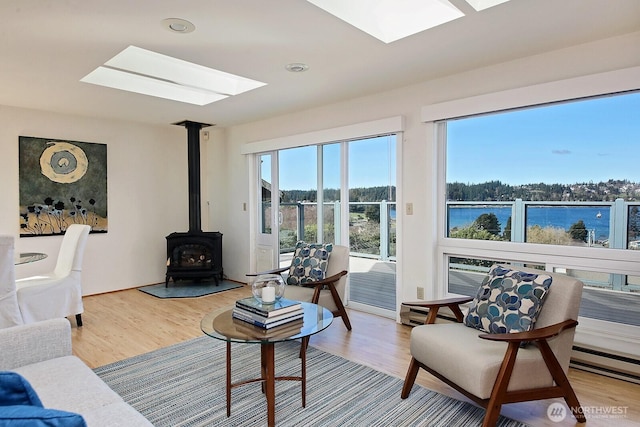 living area with a skylight, a wood stove, and wood finished floors