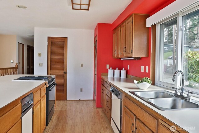 kitchen featuring electric range, dishwasher, light countertops, and a sink