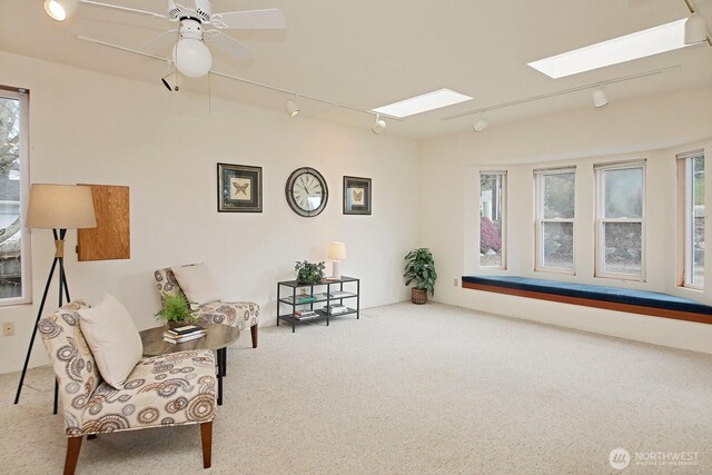 sitting room featuring track lighting, a ceiling fan, a skylight, and carpet flooring