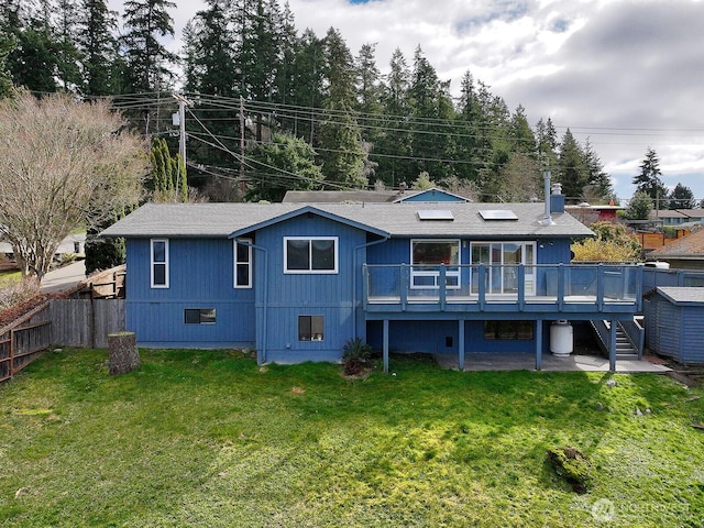 rear view of house featuring a storage unit, an outbuilding, fence, a yard, and a wooden deck