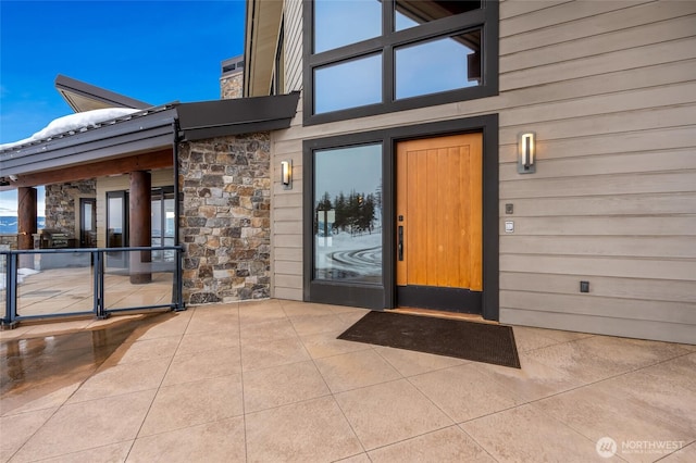 entrance to property with stone siding and a patio area